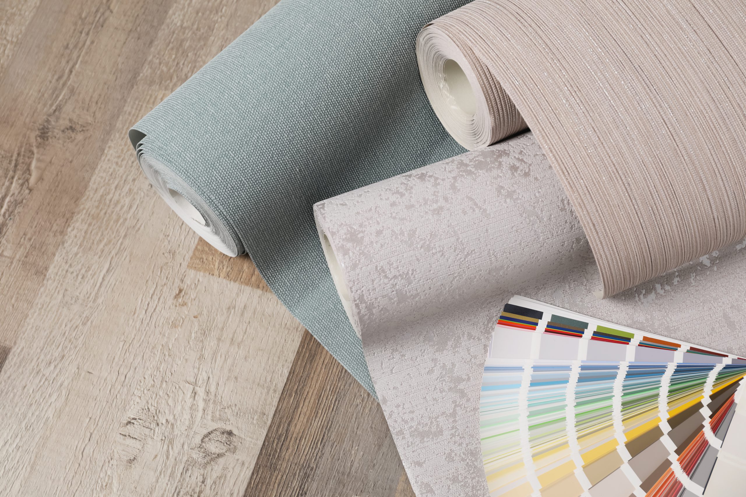 Wall paper rolls and color palette on wooden floor owned by painting company london